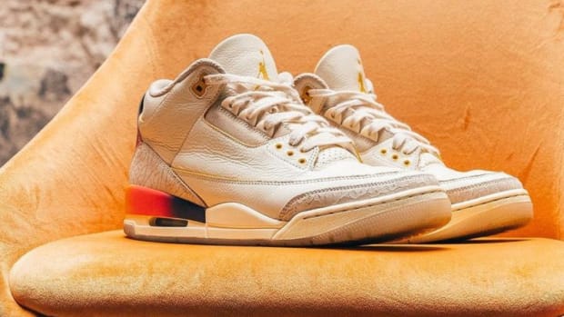 White Air Jordan sneakers sit on an orange chair.